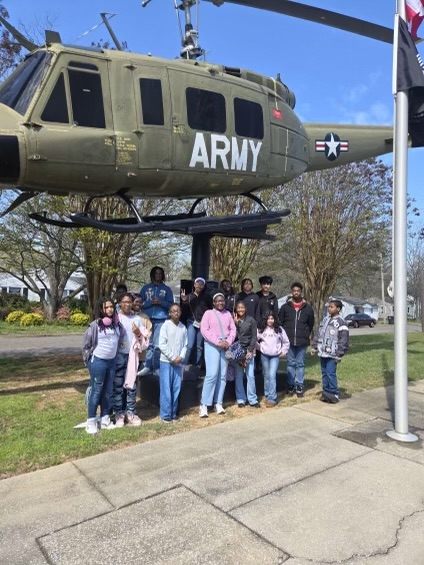 Students posed in front of a helicopter at the museum.